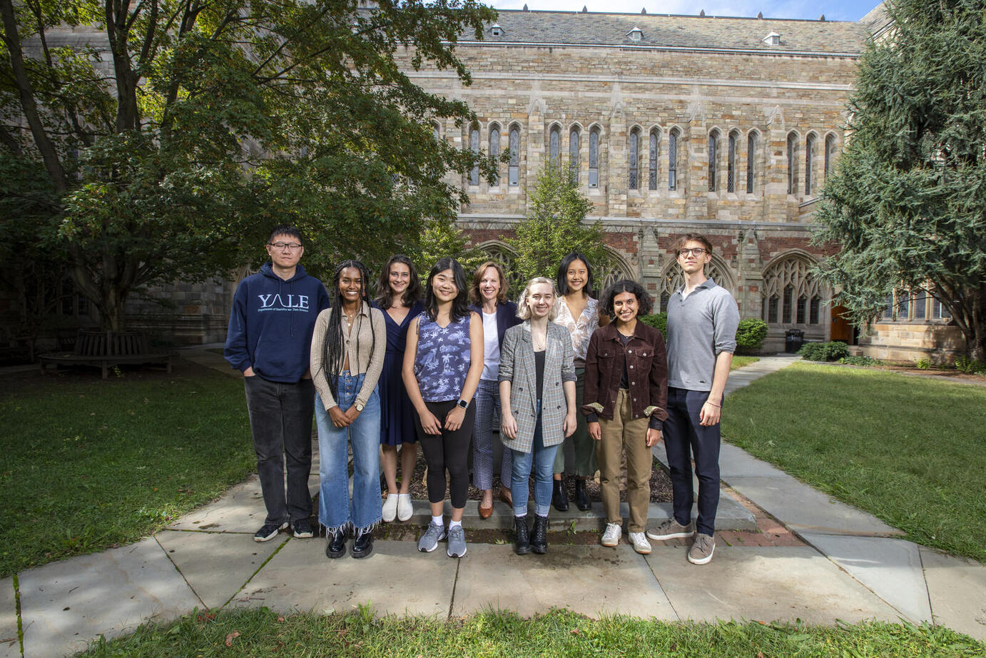 Group photo of students in a courtyard with stone and brick building in the background