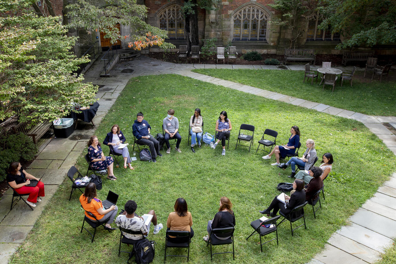 Aerial view of a group of students and staff seated in circle of chairs 