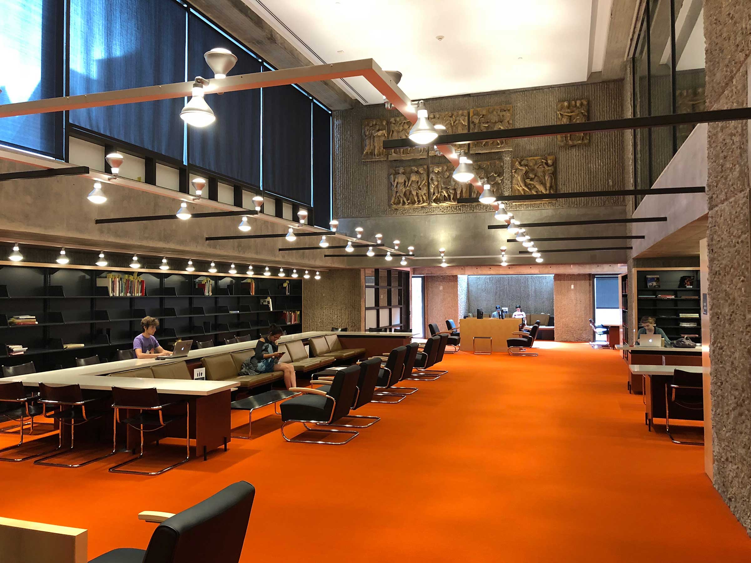 Interior view of Haas Arts Library featuring student studying at long table near book cases.