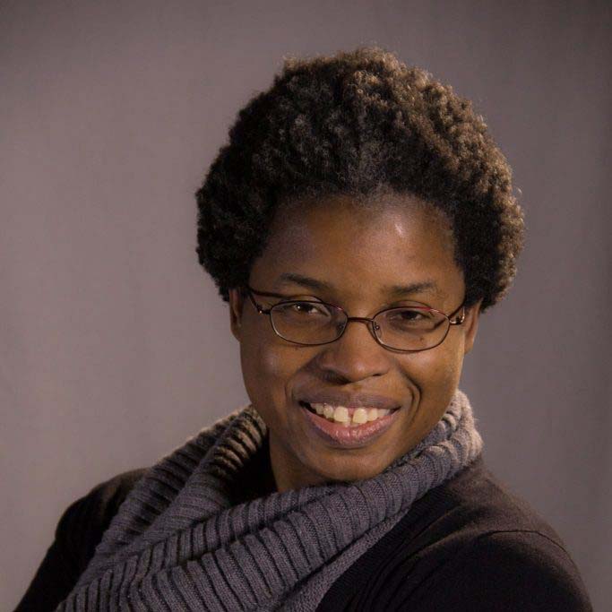 portrait of an African American woman wearing glasses and black sweater with grey top underneath