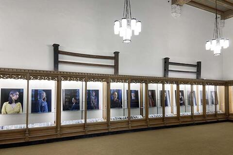 series of portraits lined up in a glass display 