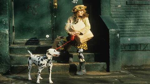Girl with curly red hair wearing a yellow hat holding a Dalmatian on a red leash.