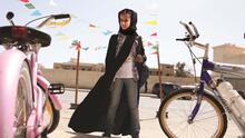 Young Saudi Arabian girl standing in between pink and white bicycles