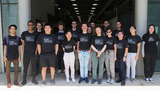 17 young male and female science students pose, wearing black t-shirts with white lettering that reads "Wright Laboratory"