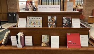 Two shelves of a book display in Bass library. On top ledge is a sign reading The Reading Resilience Project and next to it are bookmarks with photos of Zora Neale Hurston and Langston Hughes. There are nine books shown on shelves below. Two titles are Dancing after Ten and Our Voices.