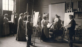 A black and white photograph of Yale art students standing at easels paitning a live model