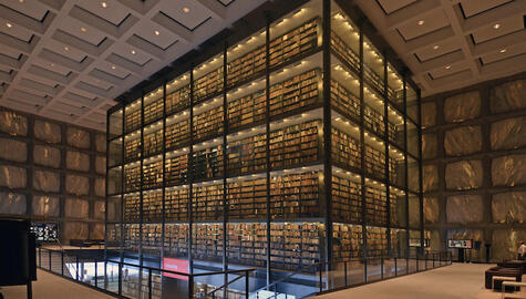 Interior of library with glass enclosed book stacks and walls made of translucent marble panels