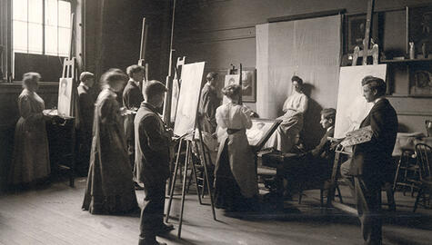 A black and white photograph of Yale art students standing at easels paitning a live model