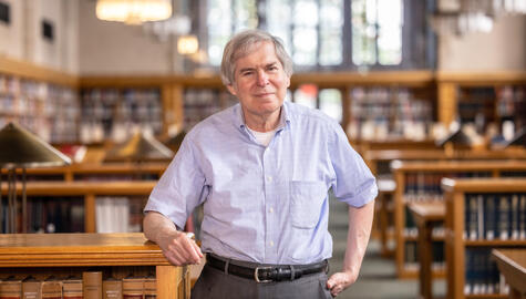 Fred Shapiro standing in the library, surrounded by shelves of books