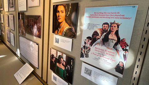 Wall of mounted images of movie stills showing women dressed in Tudor crowns and garments