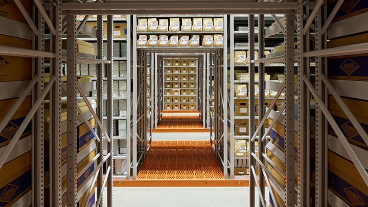 View into series of shelving with metal horizontal and vertical beams with orange flooring 