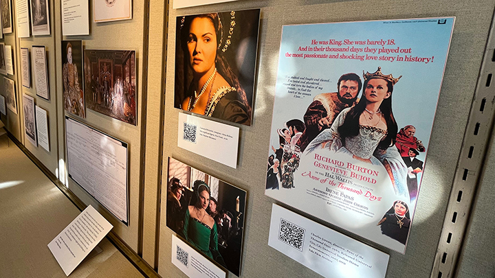 Wall of mounted images of movie stills showing women dressed in Tudor crowns and garments