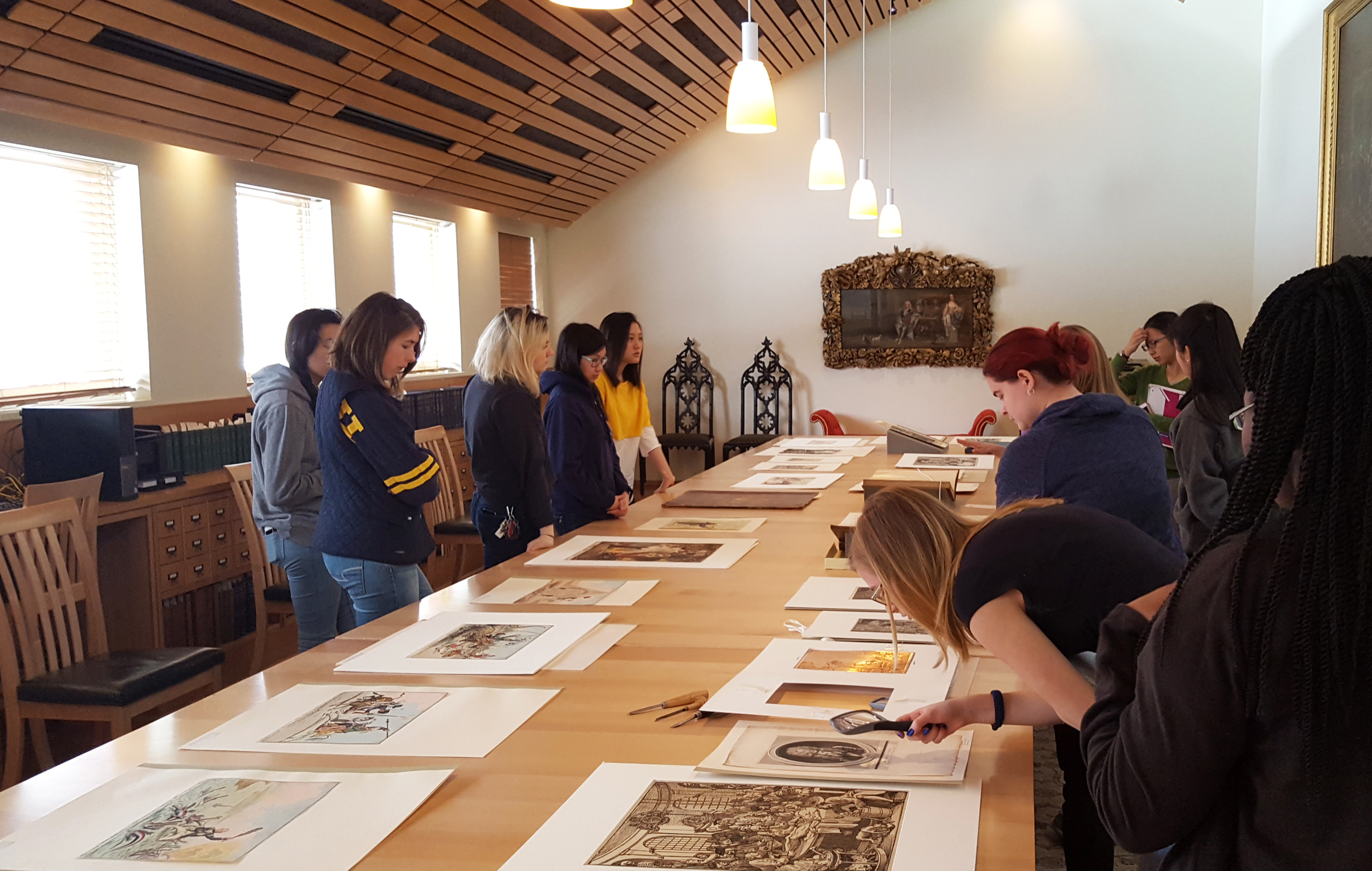 Students and researchers looking at books and prints on a long table at the Walpole Library