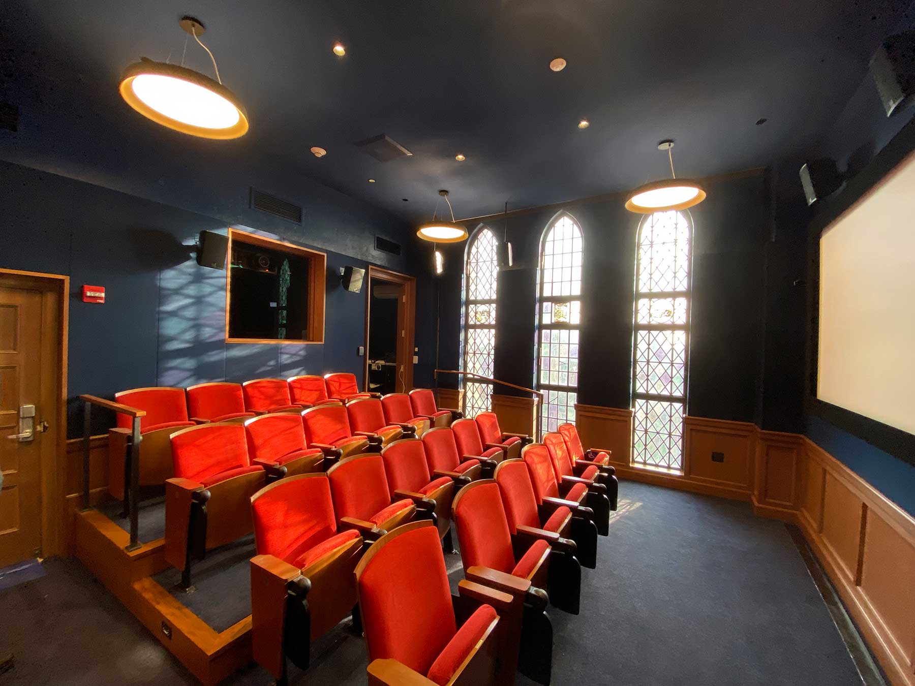 Screening room of red seats in front of a movie screen, part of the Yale Film Archive